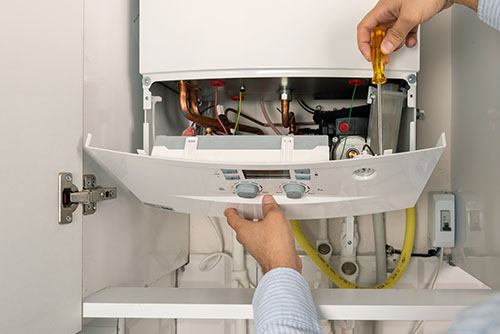 Heating technician repairing a residential boiler in Pacifica