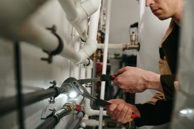 Technician inspecting commercial plumbing pipes in Pacifica