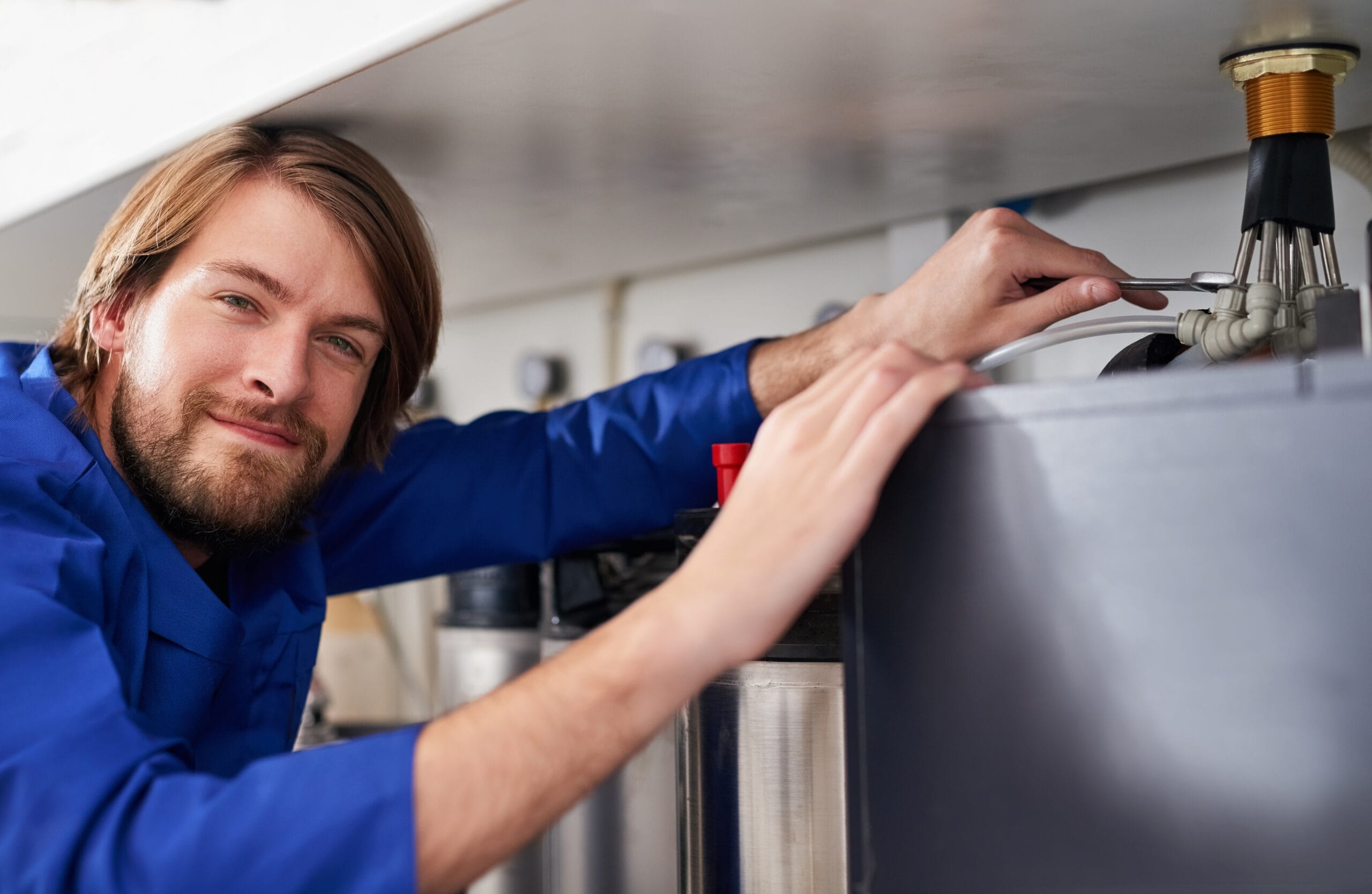 Technician servicing a residential water heater tank in Pacifica